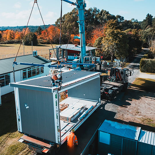 TDM Transport crane lifting a modular building unit onto a flatbed trailer, New Zealand