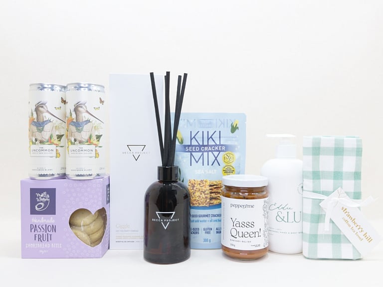 Home Treats Gift Box featuring Uncommon sparkling wine cans, Strawberry Hill tea towel, Kiki crackers, Yas Queen Relish, Molly Woppy cookies, Becca Project chocolate, and Eddy & lu home essentials.