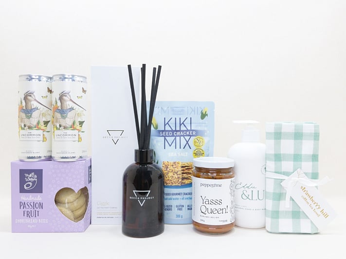 Home Treats Gift Box featuring Uncommon sparkling wine cans, Strawberry Hill tea towel, Kiki crackers, Yas Queen Relish, Molly Woppy cookies, Becca Project chocolate, and Eddy & lu home essentials.