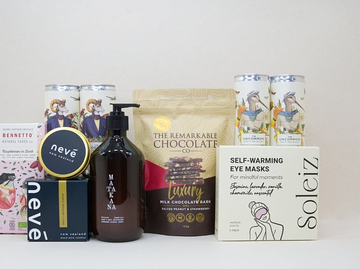 Deluxe Pamper Gift Box featuring Uncommon wine cans, Soléiz eye masks, Nevé candle, Bennetto chocolate, and Matakana Botanicals moisturiser in a premium KYND gift box.