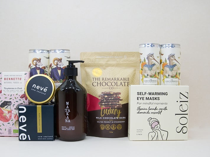 Deluxe Pamper Gift Box featuring Uncommon wine cans, Soléiz eye masks, Nevé candle, Bennetto chocolate, and Matakana Botanicals moisturiser in a premium KYND gift box.
