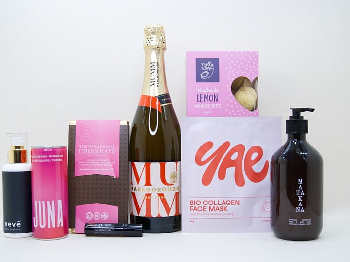Pink Celebration Gift Box featuring Mumm sparkling wine, Yae face mask, Matakana Botanicals moisturiser, Juna wellness drink, Molly Woppy cookies, and Nevé room spray in a premium KYND gift box.