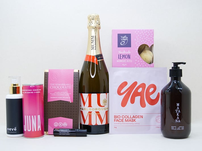 Pink Celebration Gift Box featuring Mumm sparkling wine, Yae face mask, Matakana Botanicals moisturiser, Juna wellness drink, Molly Woppy cookies, and Nevé room spray in a premium KYND gift box.