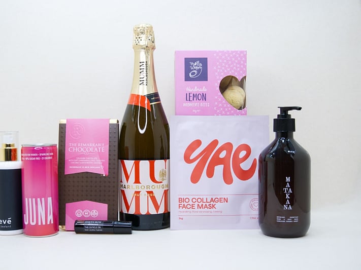 Pink Celebration Gift Box featuring Mumm sparkling wine, Yae face mask, Matakana Botanicals moisturiser, Juna wellness drink, Molly Woppy cookies, and Nevé room spray in a premium KYND gift box.