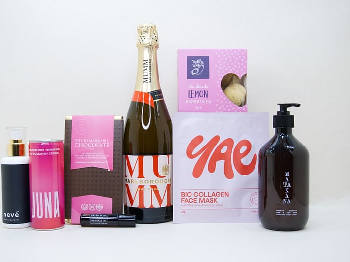 Pink Celebration Gift Box featuring Mumm sparkling wine, Yae face mask, Matakana Botanicals moisturiser, Juna wellness drink, Molly Woppy cookies, and Nevé room spray in a premium KYND gift box.