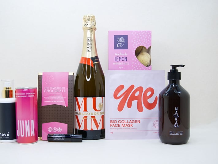 Pink Celebration Gift Box featuring Mumm sparkling wine, Yae face mask, Matakana Botanicals moisturiser, Juna wellness drink, Molly Woppy cookies, and Nevé room spray in a premium KYND gift box.