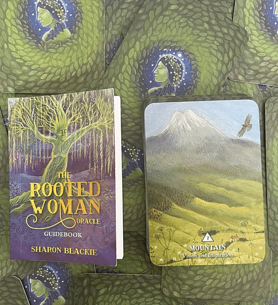 The rooted woman guidebook pictured on the back side of a range of The Rooted Woman Oracle Cards and the Mountain Card Shown 
