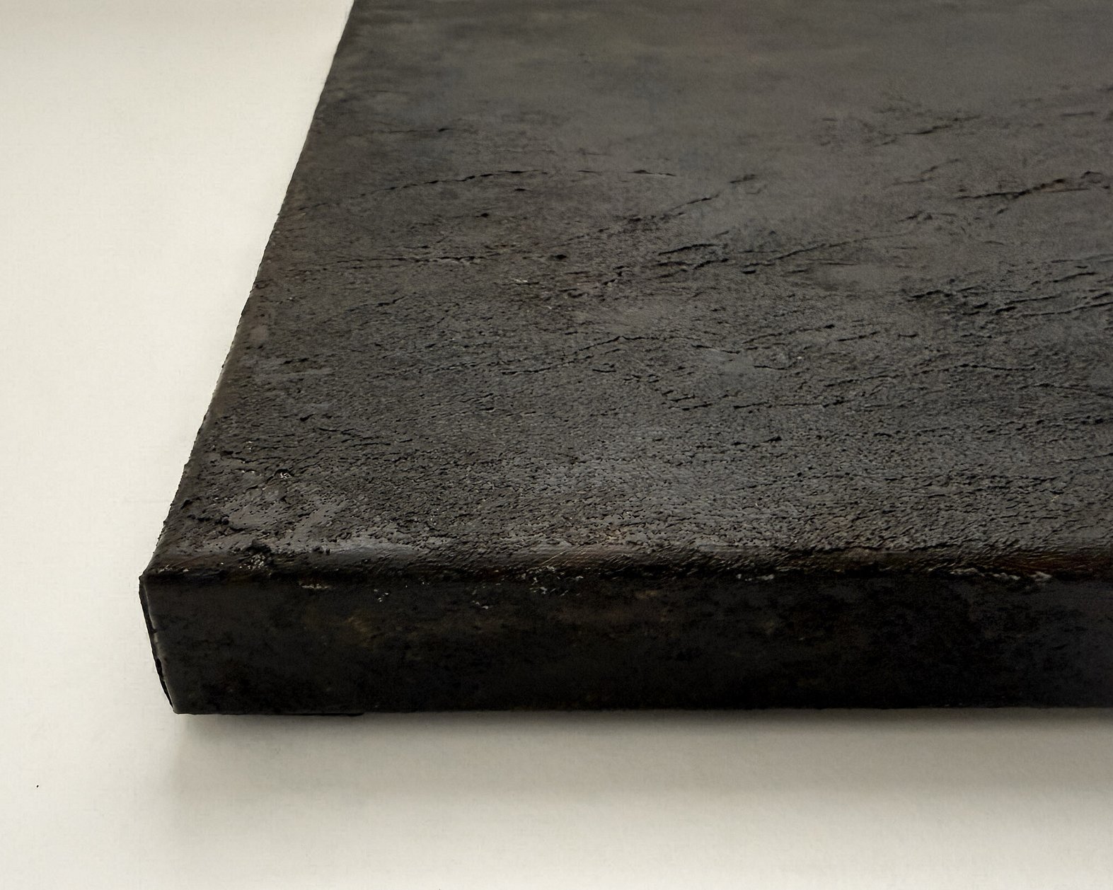 side view of canvas showing a heavily textured deep cocoa-toned mineral surface, raised texture and canvas depth
