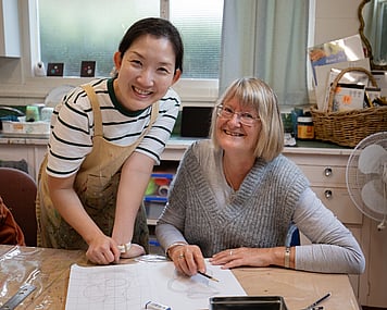 Art tutor showing woman artist drawing techniques.