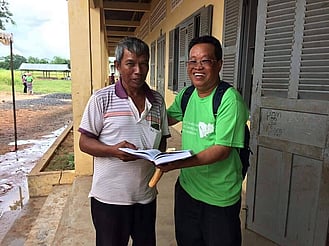 Cambodian man receiving gift of a bible
