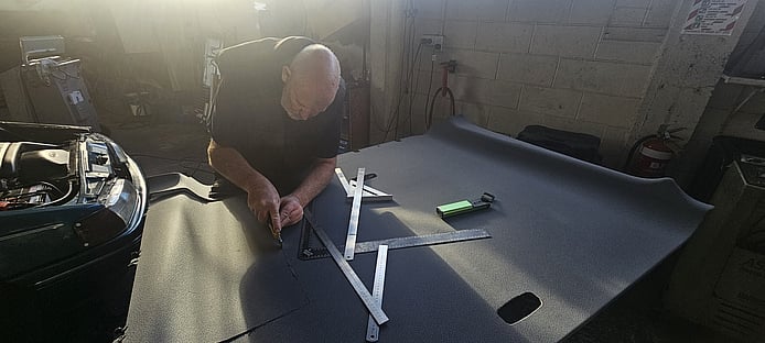 CoolCar technician cutting carpet to fit box housing of newly installed custom A/C unit in van
