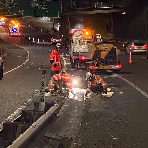 Crewmix machine pouring concrete on motorway during night road works