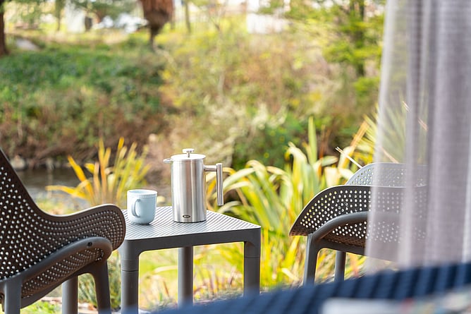 View from a Two Rivers Ohakune guest suite, looking down to the rivers with coffee on a table setting.