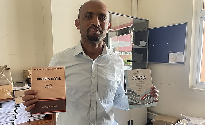 NT scholar Dr Tekalign Duguma holding two of his own commentaries on Matthew in different Ethiopian languages. Dr Duguma runs theological publishing house Onesimus out of the EGST offices.