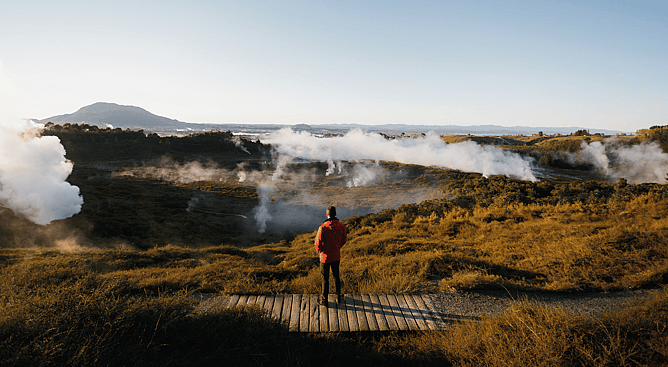 Person on wooden boardwalk looking out over steam vents at Craters of the Moon Taupo