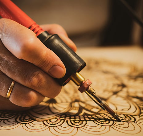 Pyrographing a mandala. Jodie Appleton Pyrography workshop for Waimarino Art Awards 2026. Image by Photo by <a href="https://unsplash.com/@superwillyfoc?utm_source=unsplash&utm_medium=referral&utm_content=creditCopyText">Guillermo Latorre</a> on <a href="https://unsplash.com/photos/person-holding-red-and-black-hand-tool-PN_mcoUDpbY?utm_source=unsplash&utm_medium=referral&utm_content=creditCopyText">Unsplash</a>