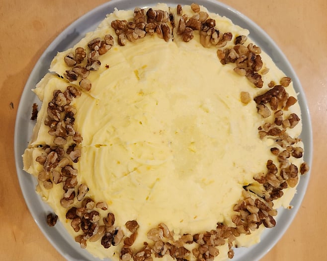 Full carrot cake topped with cream cheese icing and pistachio garnish
