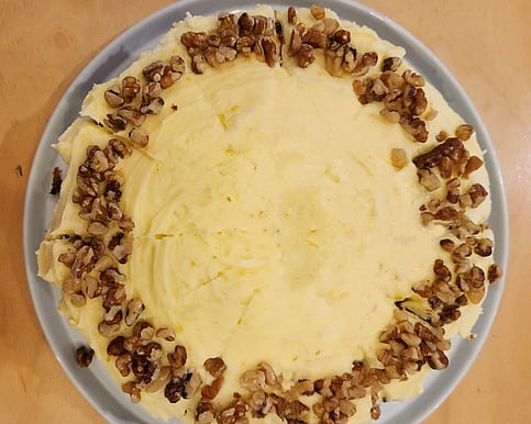 Full carrot cake topped with cream cheese icing and pistachio garnish