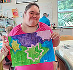 Arts for Health artists Darling holding a colourful painting in Open Studio in Hamilton