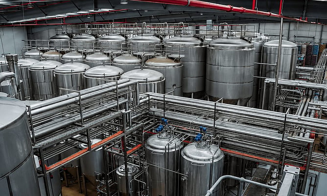 Rows of stainless steel fermentation tanks and process piping inside the Brick Lane Brewing brewhouse in Dandenong