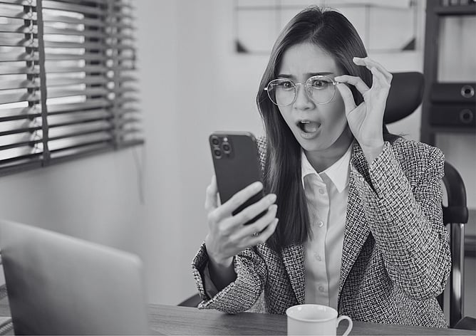 Business owner reacting with shock while reading a message on her phone