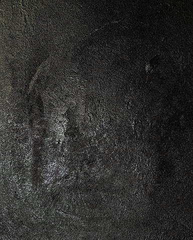detail image of warm black acrylic and silica sand surface, showing densely layered granular texture, shallow depressions, irregular raised ridges and fissures with subtle variations in sheen revealed by directional light 