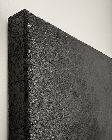 side view of warm black atmospheric landscape painting on linen, showing the acrylic and silica sand texture, with a rough granular finish, subtle sheen catching the light and canvas depth