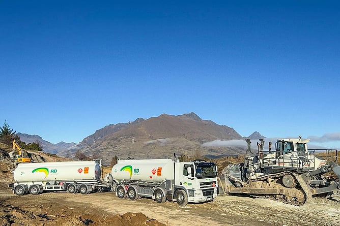 RD Petroleum fuel tankers at a Queenstown construction site with excavators and mountains in the background