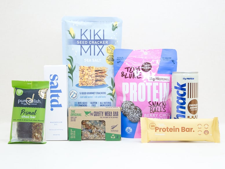 Wellness Gift Box featuring Saltd magnesium spray, Nothing Naughty protein bar, Tom & Luke protein balls, Pure Delish protein muesli bar, Schick protein drink, Kikki crackers, and healthy NZ-made snacks.