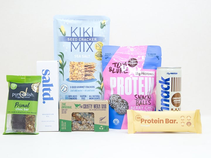 Wellness Gift Box featuring Saltd magnesium spray, Nothing Naughty protein bar, Tom & Luke protein balls, Pure Delish protein muesli bar, Schick protein drink, Kikki crackers, and healthy NZ-made snacks.