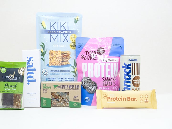 Wellness Gift Box featuring Saltd magnesium spray, Nothing Naughty protein bar, Tom & Luke protein balls, Pure Delish protein muesli bar, Schick protein drink, Kikki crackers, and healthy NZ-made snacks.