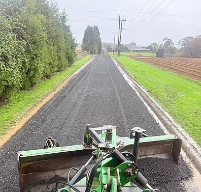 Recycled Asphalt product being spread by a grader