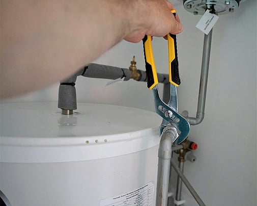 Technician servicing the pipework on a hot water heat pump cylinder