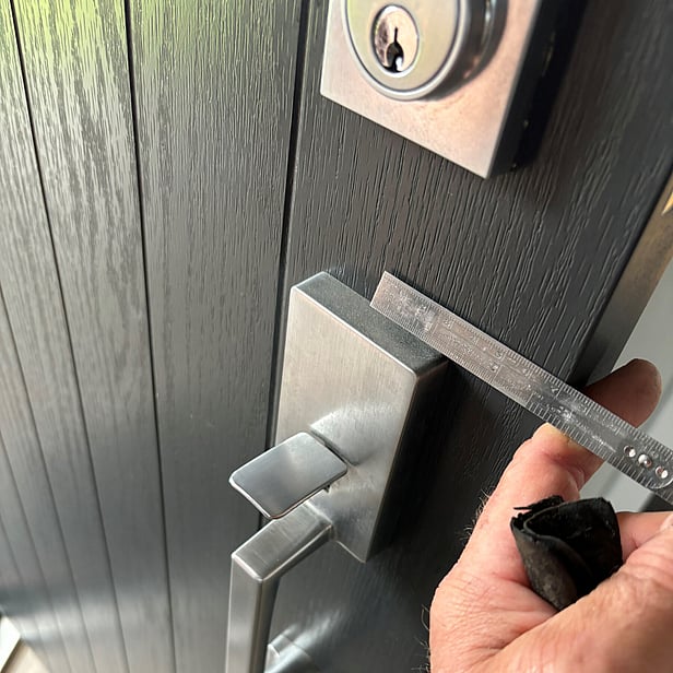 A picture of one of our professional locksmiths measuring a door for a new electronic lock installation