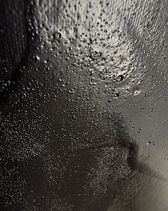 detail image of warm black acrylic and silica sand surface, showing glossy pooled paint with dense pitting, granular texture and variations in sheen revealed by directional light 