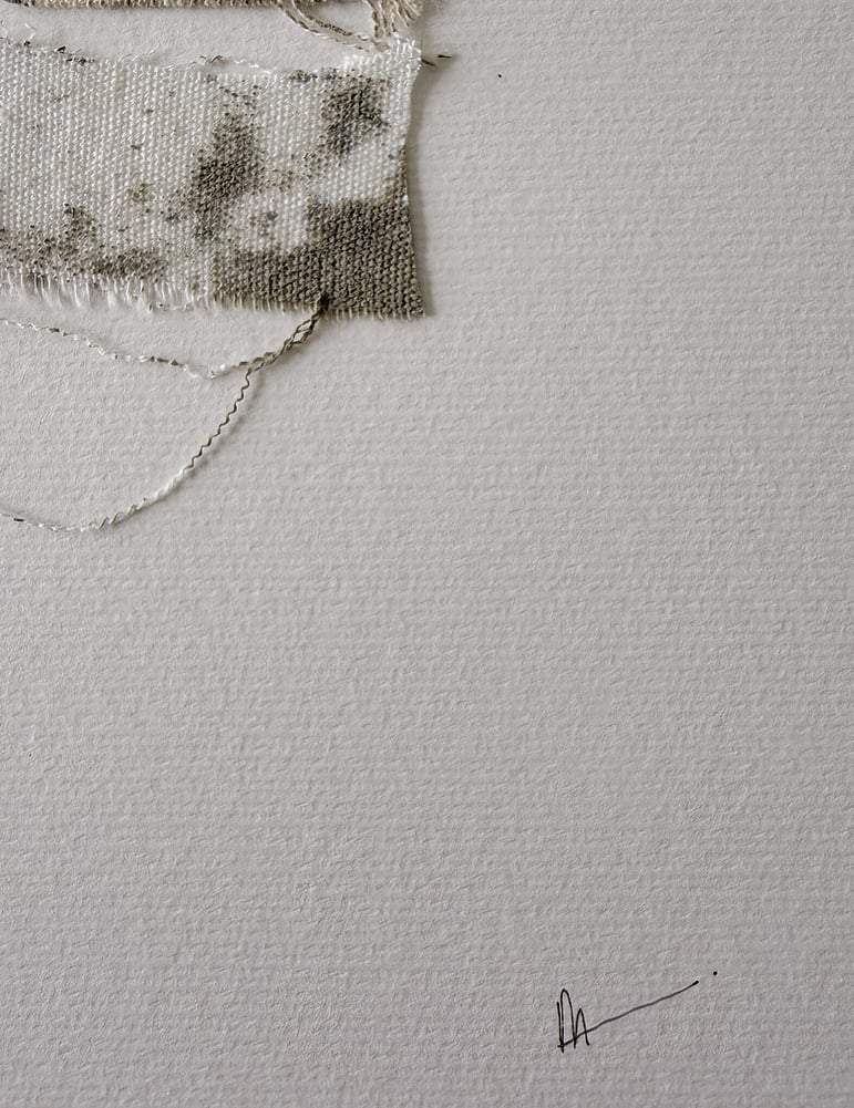 close-up image of soft white fabriano surface texture, layered repurposed pale cream cotton fragments blotted with green-grey acrylic, visible weave texture, soft frayed edges and handwritten signature in lower right corner 