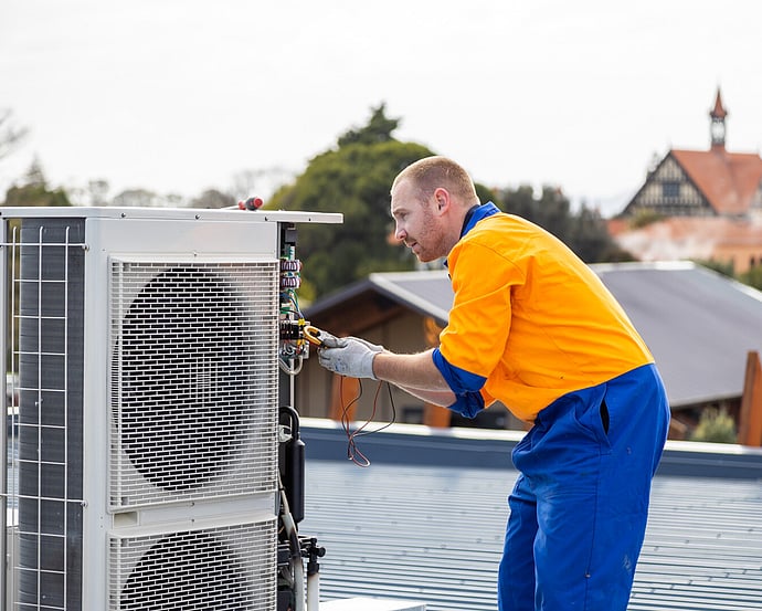 Technician carrying out maintenance on a rooftop outdoor heat pump unit