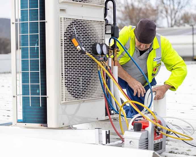 Technician using refrigerant gauges to diagnose a fault on an outdoor heat pump