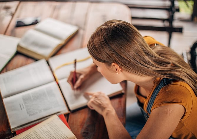 Young woman studying and writing notes in a notebook