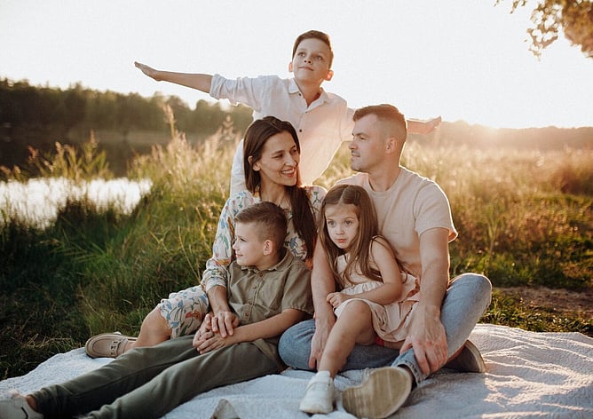 Family of parents and two children sitting together outdoors at sunset