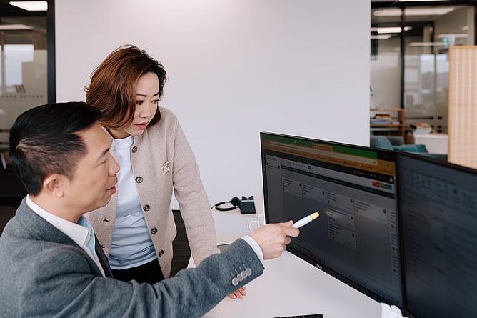 Two colleagues reviewing information together on a computer screen