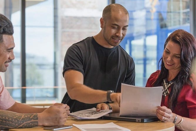 Three colleagues reviewing paperwork together at a table