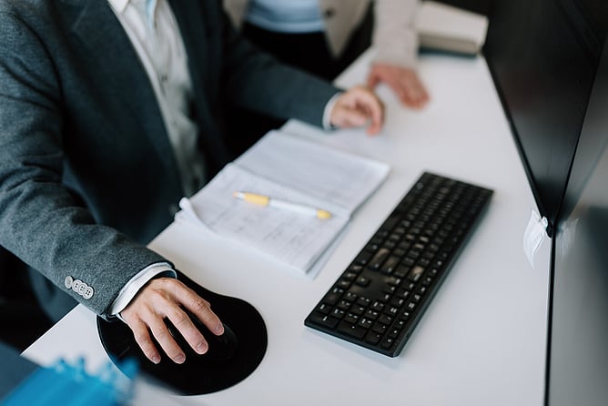 Person signing or writing in a document at a desk