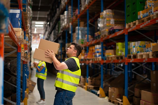 Warehouse worker lifting a box, wearing high-visibility safety vest