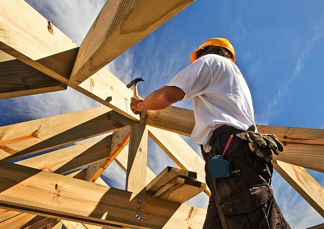 Tradesperson working on timber roof framing at a construction site