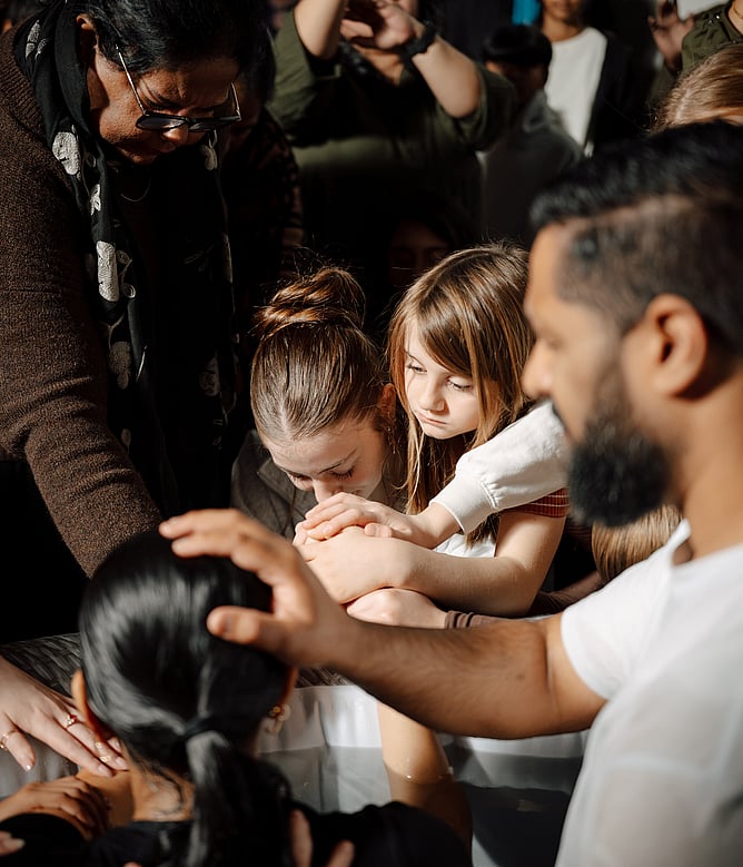 Violet prays for her friend Mikayla (in pool) at her baptism, alongside family and friends.