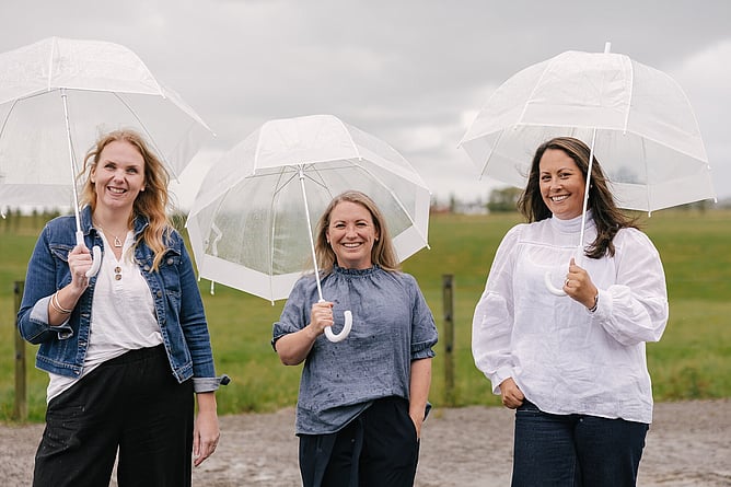 Cheyenne, Anna and Amber together on a farm holding umbrellas