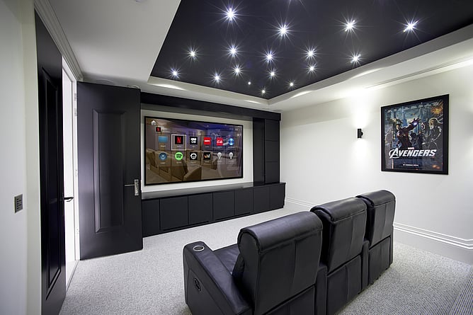 Dedicated home cinema room with star ceiling lights, large display screen, leather recliner seats, and smart home AV control interface