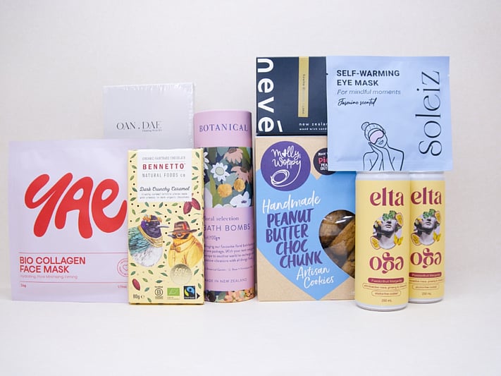 Care Package Gift Box featuring an OAN DAE wish paper kit, Soleiz eye masks, Nevé candle, floral bath bombs, Molly Woppy peanut butter cookies, YAE face mask, Bennetto chocolate, and Elta Ego self-care products, beautifully packaged to encourage relaxation and wellbeing