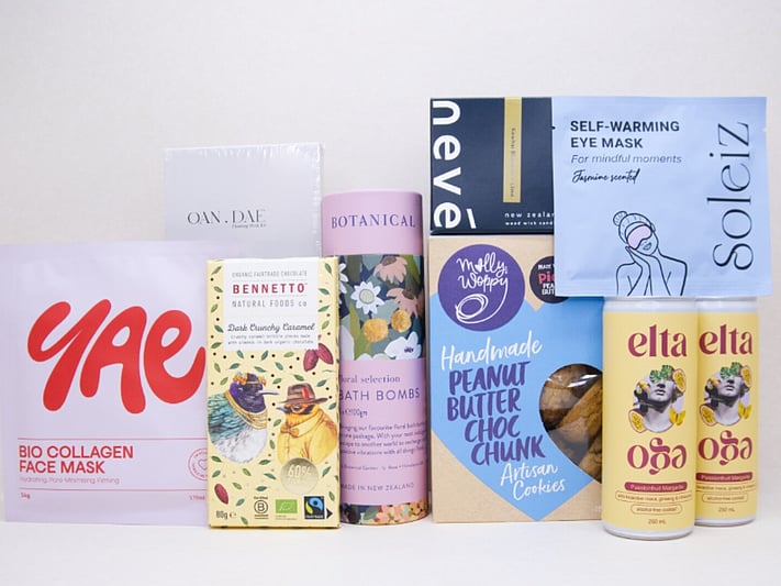 Care Package Gift Box featuring an OAN DAE wish paper kit, Soleiz eye masks, Nevé candle, floral bath bombs, Molly Woppy peanut butter cookies, YAE face mask, Bennetto chocolate, and Elta Ego self-care products, beautifully packaged to encourage relaxation and wellbeing